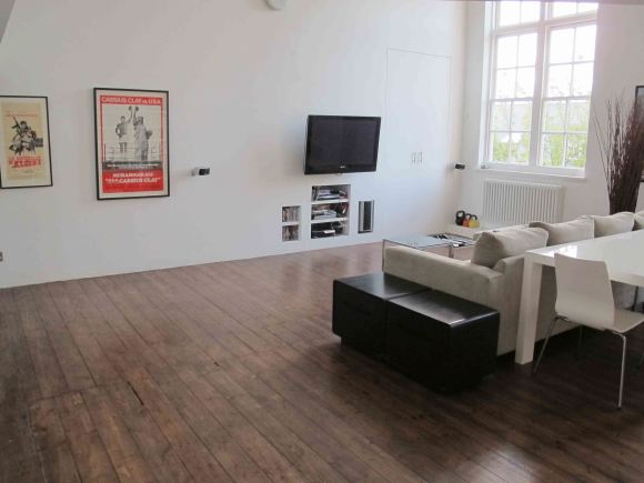Loft apartment in a converted Victorian school with high ceilings, arched windows and a wall of books.