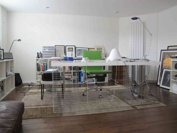 Loft apartment in a converted Victorian school with high ceilings, arched windows and a wall of books.