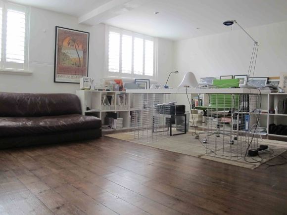 Loft apartment in a converted Victorian school with high ceilings, arched windows and a wall of books.