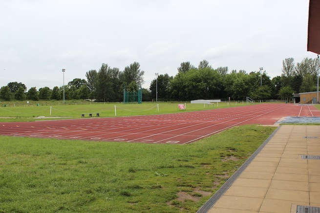 Athletics track surrounding various athletic setups with a playing field and tennis courts adjacent.