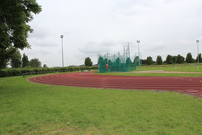 Athletics track surrounding various athletic setups with a playing field and tennis courts adjacent.