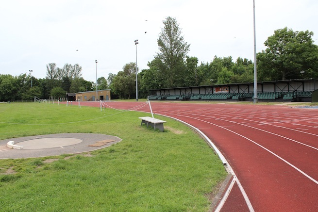 Athletics track surrounding various athletic setups with a playing field and tennis courts adjacent.