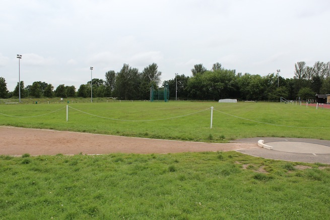 Athletics track surrounding various athletic setups with a playing field and tennis courts adjacent.