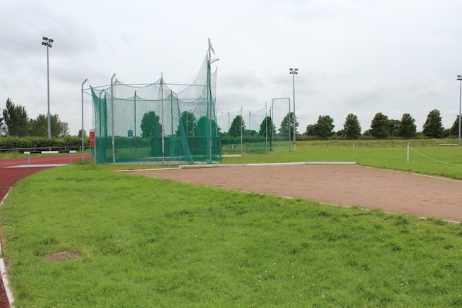 Athletics track surrounding various athletic setups with a playing field and tennis courts adjacent.
