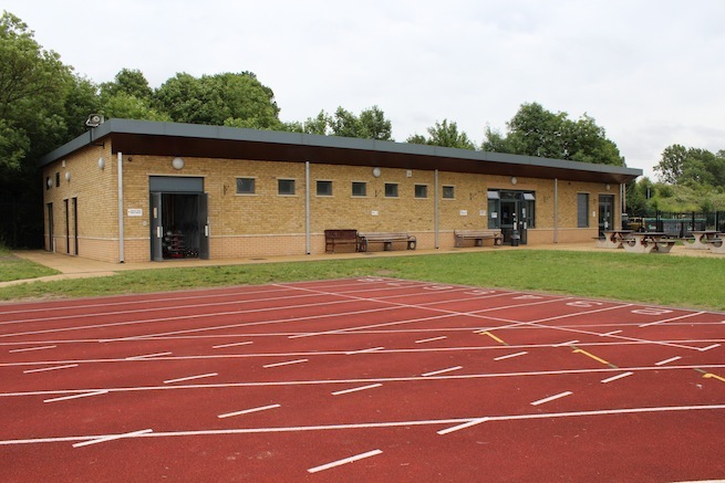 Athletics track surrounding various athletic setups with a playing field and tennis courts adjacent.