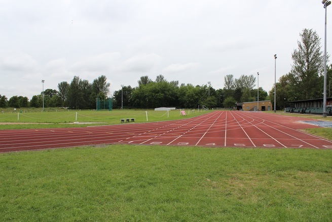 Athletics track surrounding various athletic setups with a playing field and tennis courts adjacent.