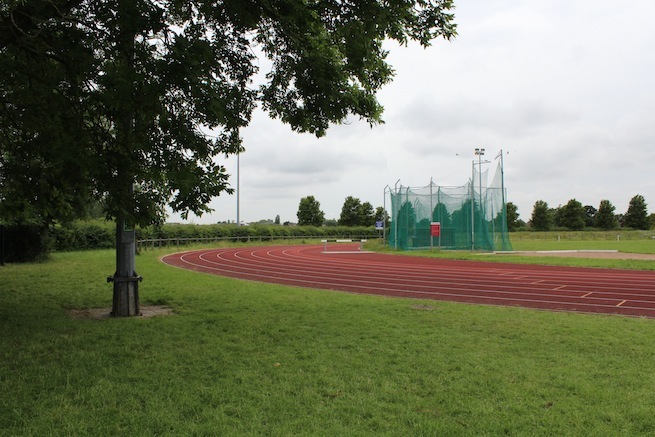Athletics track surrounding various athletic setups with a playing field and tennis courts adjacent.
