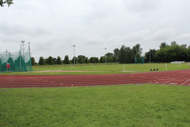 Athletics track surrounding various athletic setups with a playing field and tennis courts adjacent.