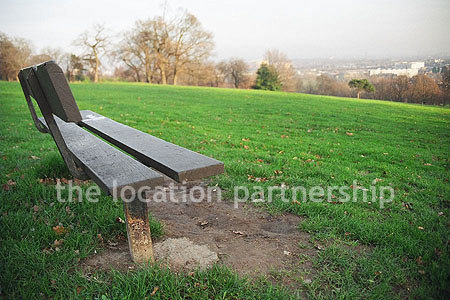 Bench on hill overlooking parkland and views of London