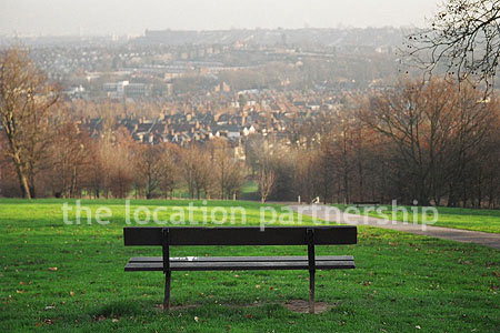 Bench on hill overlooking parkland and views of London