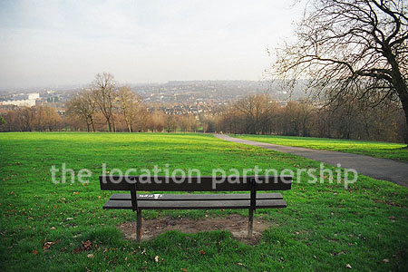 Bench on hill overlooking parkland and views of London