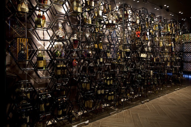 A stylish cocktail bar with glamorous surroundings. The bar boasts impressive storage cabinets and contemporary art work.