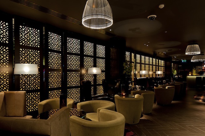 A stylish cocktail bar with glamorous surroundings. The bar boasts impressive storage cabinets and contemporary art work.