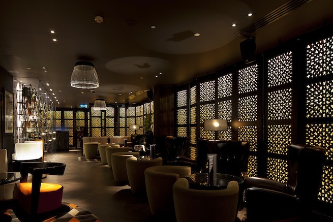 A stylish cocktail bar with glamorous surroundings. The bar boasts impressive storage cabinets and contemporary art work.
