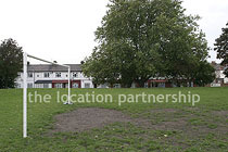 Small 5-a-side sized football pitch with urban backdrop of pylons and houses.