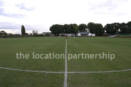 Football / cricket pitches with semi-urban backdrop and pavillion.