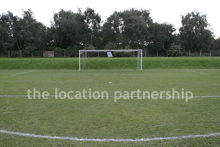 Football / cricket pitches with semi-urban backdrop and pavillion.