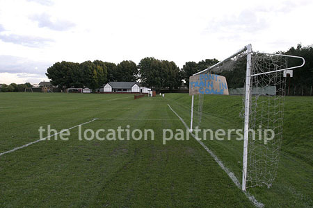 Football / cricket pitches with semi-urban backdrop and pavillion.