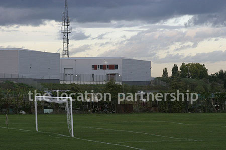 Football / cricket pitches with semi-urban backdrop and pavillion.