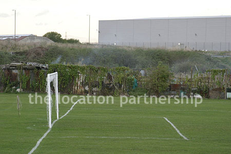 Football / cricket pitches with semi-urban backdrop and pavillion.