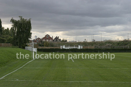 Football / cricket pitches with semi-urban backdrop and pavillion.
