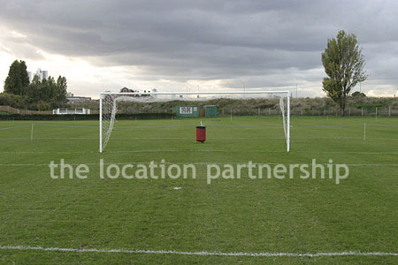 Football / cricket pitches with semi-urban backdrop and pavillion.