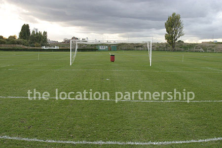 Football / cricket pitches with semi-urban backdrop and pavillion.