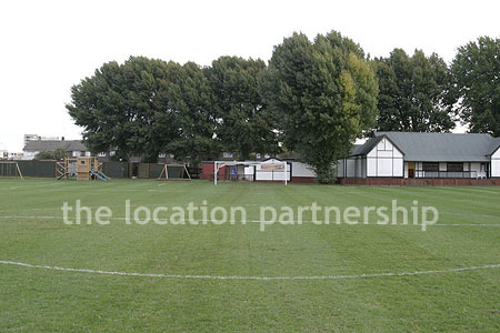 Football / cricket pitches with semi-urban backdrop and pavillion.
