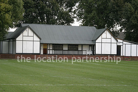 Football / cricket pitches with semi-urban backdrop and pavillion.