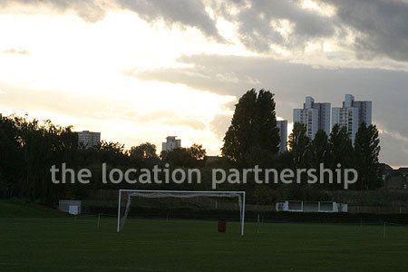 Football / cricket pitches with semi-urban backdrop and pavillion.