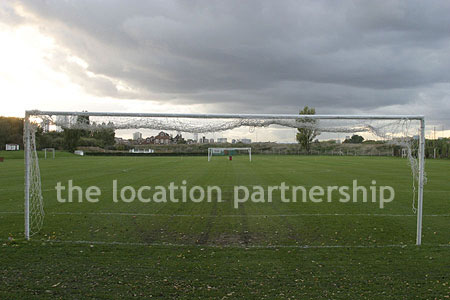 Football / cricket pitches with semi-urban backdrop and pavillion.