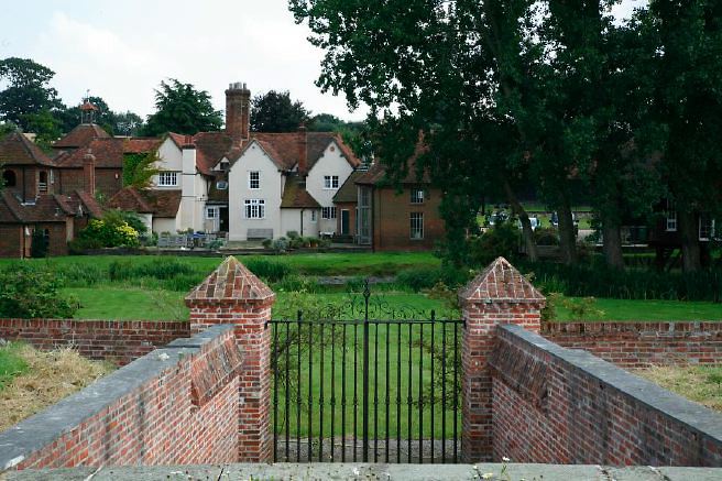 Characterful exterior and gardens of beautiful country house with treehouse, outbuildings, barns, swimming pool and tennis court.