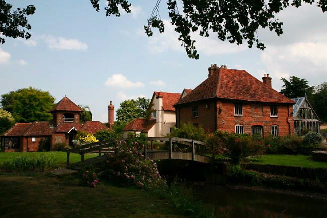 Characterful exterior and gardens of beautiful country house with treehouse, outbuildings, barns, swimming pool and tennis court.
