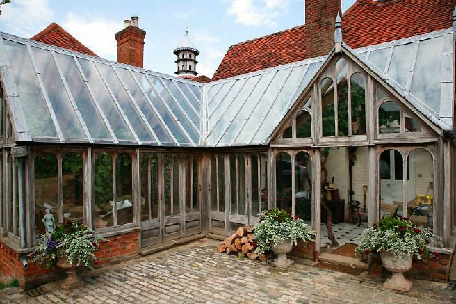 Characterful exterior and gardens of beautiful country house with treehouse, outbuildings, barns, swimming pool and tennis court.