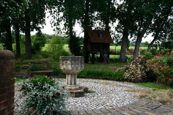 Characterful exterior and gardens of beautiful country house with treehouse, outbuildings, barns, swimming pool and tennis court.