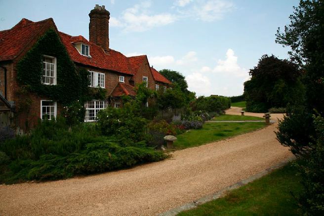 Characterful exterior and gardens of beautiful country house with treehouse, outbuildings, barns, swimming pool and tennis court.
