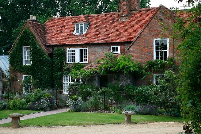 Characterful exterior and gardens of beautiful country house with treehouse, outbuildings, barns, swimming pool and tennis court.