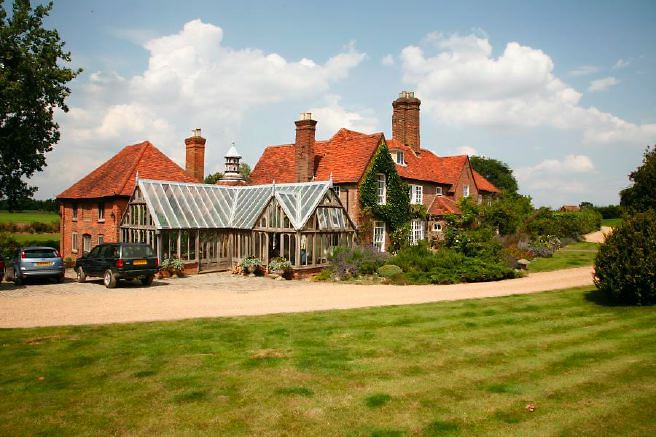 Characterful exterior and gardens of beautiful country house with treehouse, outbuildings, barns, swimming pool and tennis court.