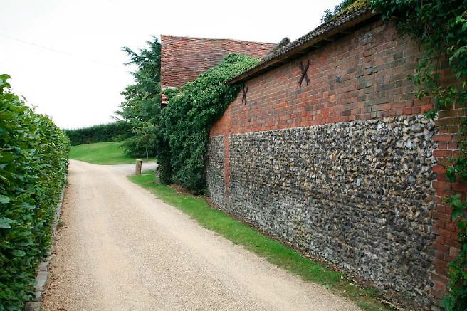 Characterful exterior and gardens of beautiful country house with treehouse, outbuildings, barns, swimming pool and tennis court.
