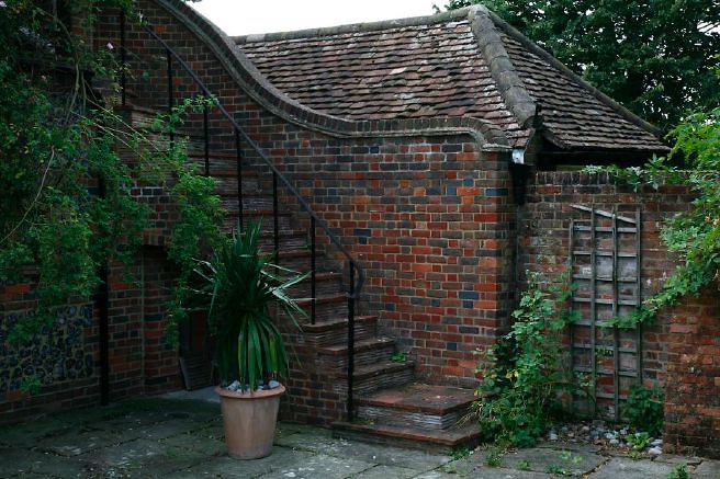 Characterful exterior and gardens of beautiful country house with treehouse, outbuildings, barns, swimming pool and tennis court.