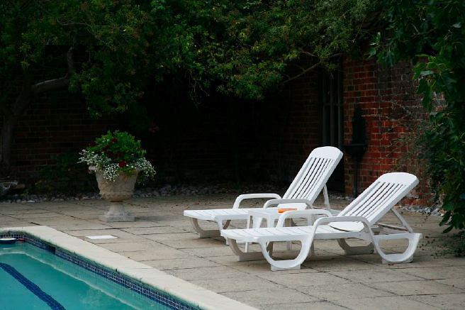 Characterful exterior and gardens of beautiful country house with treehouse, outbuildings, barns, swimming pool and tennis court.