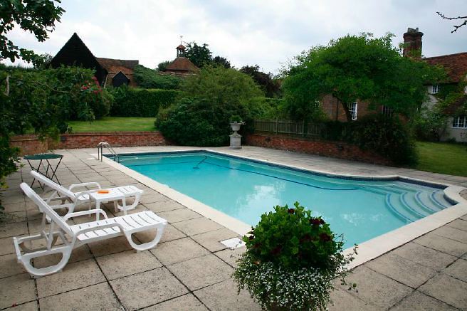 Characterful exterior and gardens of beautiful country house with treehouse, outbuildings, barns, swimming pool and tennis court.