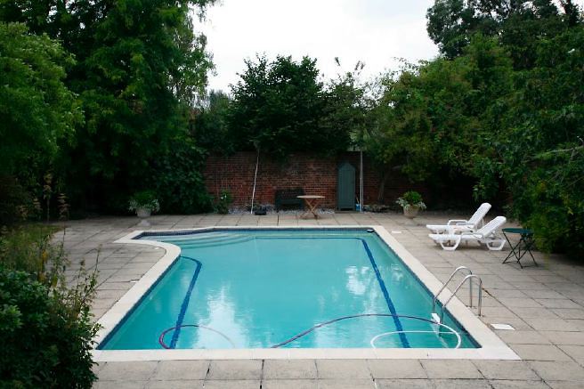 Characterful exterior and gardens of beautiful country house with treehouse, outbuildings, barns, swimming pool and tennis court.