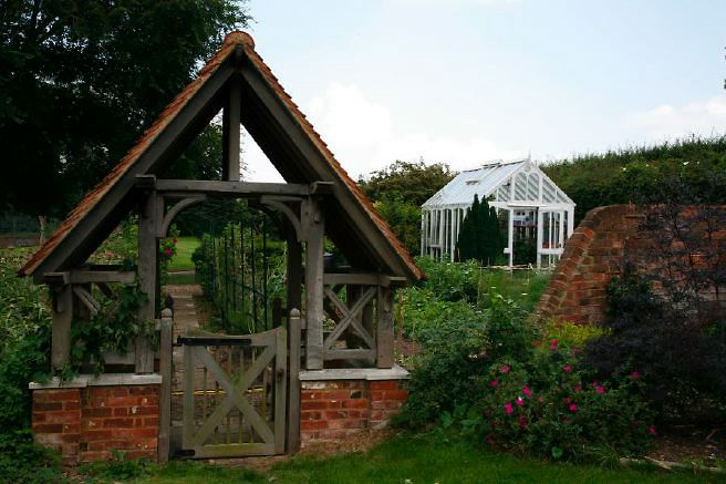 Characterful exterior and gardens of beautiful country house with treehouse, outbuildings, barns, swimming pool and tennis court.