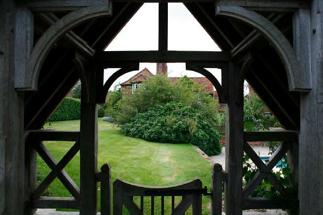 Characterful exterior and gardens of beautiful country house with treehouse, outbuildings, barns, swimming pool and tennis court.