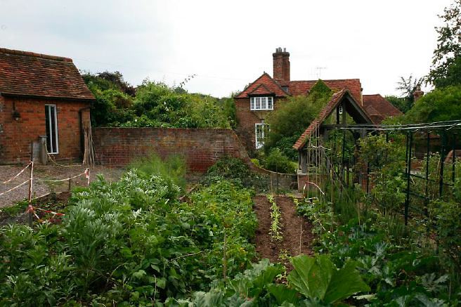 Characterful exterior and gardens of beautiful country house with treehouse, outbuildings, barns, swimming pool and tennis court.