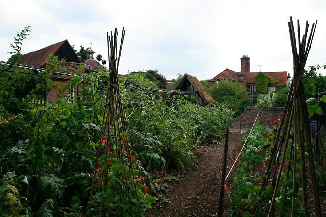 Characterful exterior and gardens of beautiful country house with treehouse, outbuildings, barns, swimming pool and tennis court.