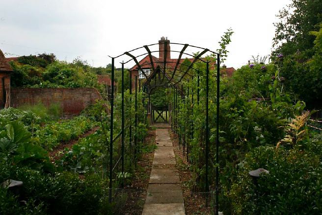 Characterful exterior and gardens of beautiful country house with treehouse, outbuildings, barns, swimming pool and tennis court.