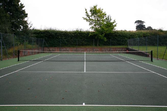 Characterful exterior and gardens of beautiful country house with treehouse, outbuildings, barns, swimming pool and tennis court.