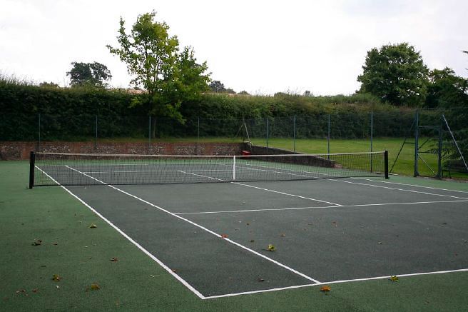 Characterful exterior and gardens of beautiful country house with treehouse, outbuildings, barns, swimming pool and tennis court.